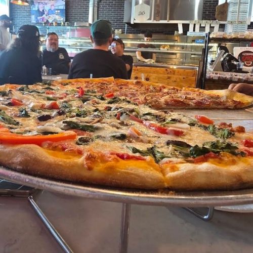 vegetable pizza on serving tray on pizza bar table