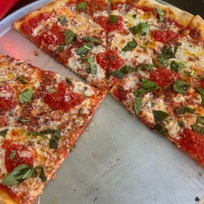 half eaten pizza with fresh tomatoes and basil