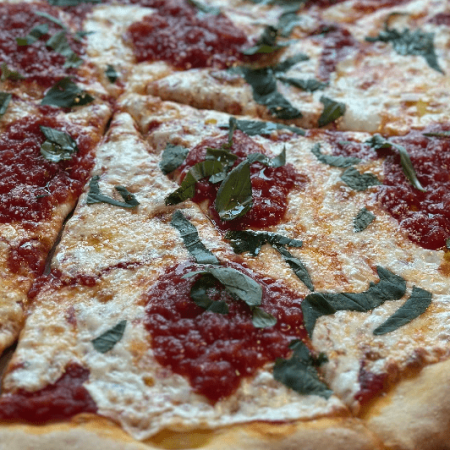 close up of pizza with homemade tomato sauce and basil
